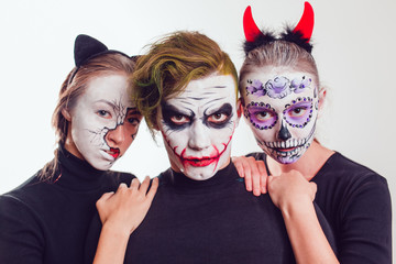 Two girls and a guy with Halloween face art on white background