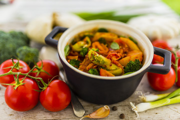 Pattison stewed with vegetables in tomato sauce on a wooden table. Vegetarian food. 