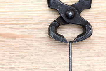 old black rusty nippers and nail on wooden background