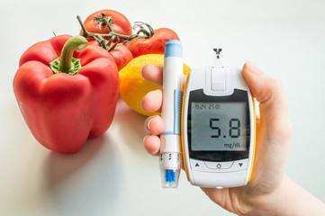 Diabetic diet, diabetes and healthy eating concept. Glucometer and vegetables in background.