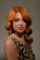 Portrait of beautiful young red haired woman with fashion makeup and hairstyle posing in the studio