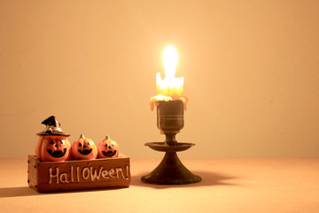 Still Life with skull, candle and Pumpkin on wooden table over orange background in night time.