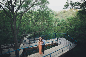 Fototapeta premium Stylish beautiful happy wedding couple kissing and embracing in Botanical Garden