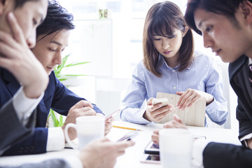 Obraz premium Four businessmen are using a smartphone