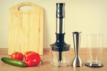 Fresh vegetables and a blender on the kitchen table, gently toned