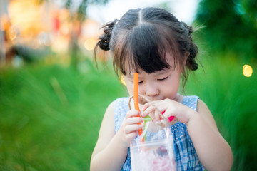 Cute asian little girl drinking water outdoors