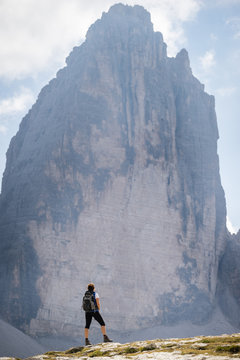 Young female tourist enjoying view of famous rock formation Tre Cime. Italian Dolomites. UNESCO World Heritage Site.