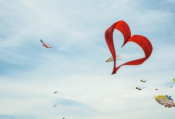 Red heart shape kite flying in blue sky 