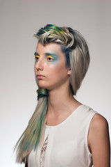 Portrait of a beautiful girl with professional hair colouring and creative make up in peacock style