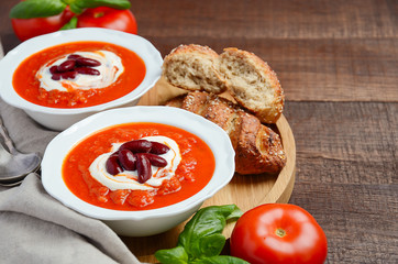 Tomato cream soup with beans on wooden background, selective focus, copy space