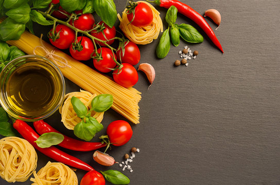 Pasta, vegetables, herbs and spices for Italian food on black background, top view, copy space