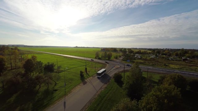 Camera follows white bus, on the road. Aerial footage. Autumn landscape.