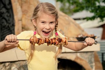 Little beautiful smiling girl with pleasure eats kebab outdoor a
