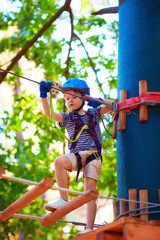 Fototapeta premium young boy passing the cable route high among trees, extreme sport in adventure park