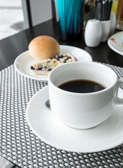 Black coffee with bread on table in morning