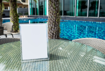 Naklejka premium Signboard blank on glass table at side swimming pool
