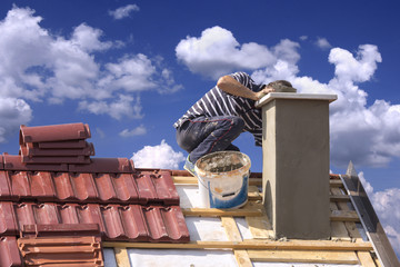 Roofer builder worker repairing a chimney stack on a roof house - 121792228
