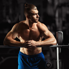 Fototapeta premium Attractive muscular bodybuilder guy prepare to do exercises with barbell in a gym