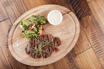 Top blade steak with salad and sauce. Wooden background