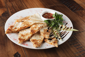 quesadilla with beef and chicken on brown wood table. quesadilla and sauce.