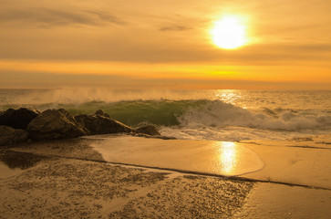 Waves crushing over rocks at sunset