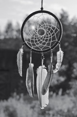 Dream catcher hanging outdoors, monochrome. Native american spiritual symbol