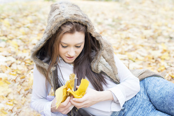 Portrait of young woman lying on autumn leaves.