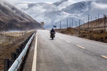 Biker motorcycle on the road beautiful winter in Tibet under snow mountain, Sichuan, China