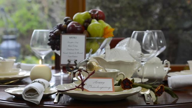 Elegant formal Thanksgiving table in front of garden window, static with candle burning.