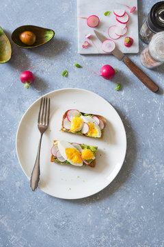 Avocado, radish and boiled egg toast. Overhead view, copy space.