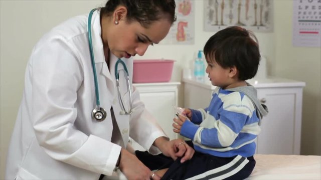 A pretty Hispanic pediatrician patiently examines a playful toddler.