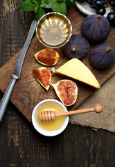 ripe figs, grapes, honey, cheese and mint leaves on a wooden background