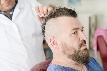 Obraz premium Male barber doing massage capillary head massager of a man