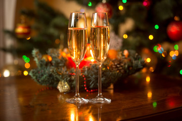 Two glasses of champagne and Christmas wreath with candles on wo
