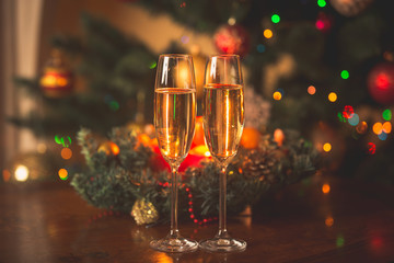 Toned image of two champagne glasses in front of Christmas wreat