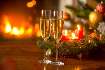 Christmas background with two champagne flutes, burning fireplac