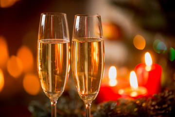 Closeup of two glasses of Champagne in front of burning candles