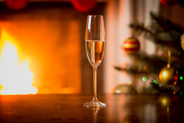 Closeup photo of glass with champagne on table in front of burni
