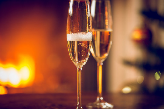 Toned image of two glasses of champagne next to the fireplace