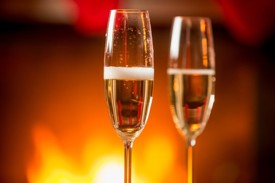 Macro image of two glasses filled with champagne with burning fi