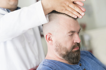 Barber makes a mohawk hairstyle at the adult man with beard