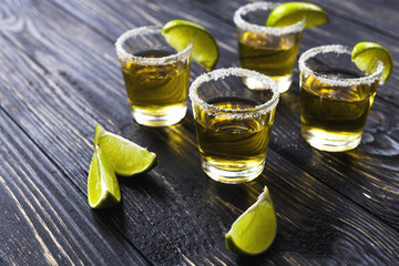 Gold tequila with lime and salt on dark table