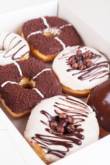 Chocolate sweet donuts with sprinkles in a box on a white background