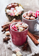 Hot chocolate with marshmallows and spices on rustic wooden table