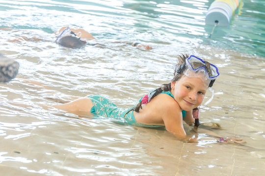young happy smiling girl swimming in water pool