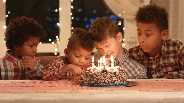 Kids near cake with candles. Boys sitting at the table. Celebrating our friend's birthday. Only the best wishes.