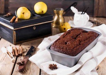Chocolate cake with pears and cinnamon on old wooden background. Selective focus.