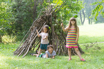 kids playing next to wooden stick house looking like indian hut,