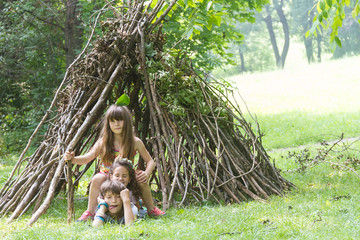 kids playing next to wooden stick house looking like indian hut, © Alena Yakusheva