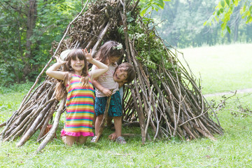 kids playing next to wooden stick house looking like indian hut,